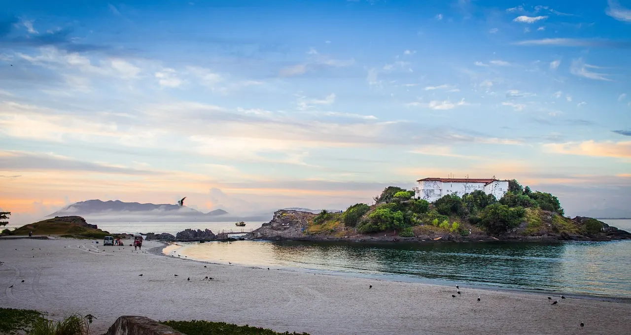 Paisagem de Cabo Frio ao entardecer, com praia, mar e céu em tons suaves
